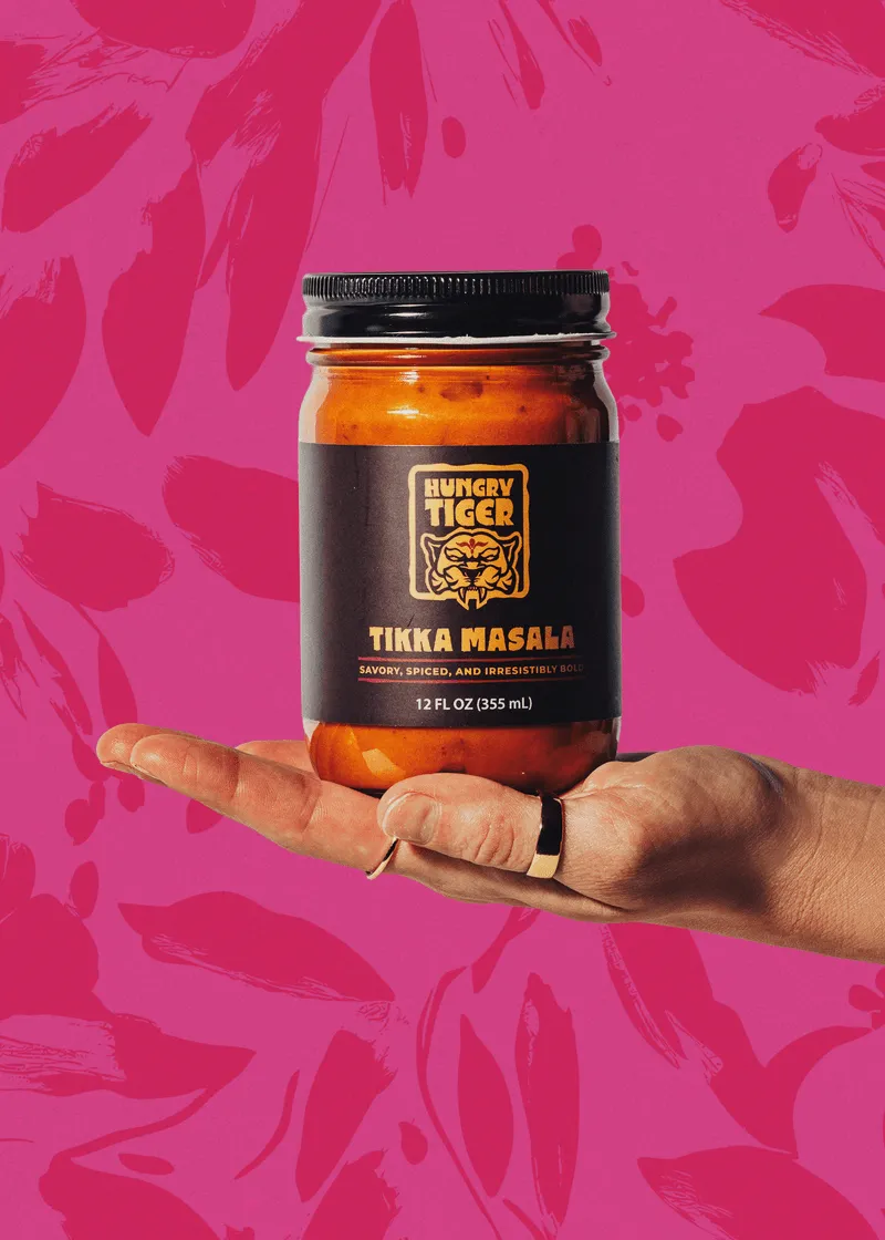 Hand holding a jar of Hungry Tiger Tikka Masala